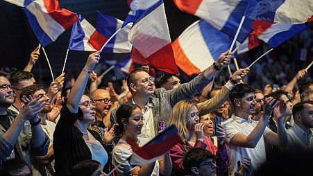 Anhänger der rechtsextremen französischen Nationalen Sammlungsbewegung schwenken am Freitag, den 24. Mai 2024, während einer Versammlung zu den bevorstehenden Europawahlen in Henin-Beaumont, Nordfrankreich, Fahnen. 