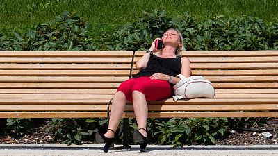 Una mujer sentada en un parque de Milán, Italia, el martes 16 de julio de 2024. 
