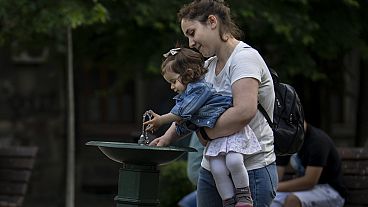 Madre e figlia a una fontanella in un giorno di canicola