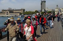 Sur cette photo du mercredi 25 mai 2016, des touristes se promènent sur le port Maremagnum à Barcelone, en Espagne.