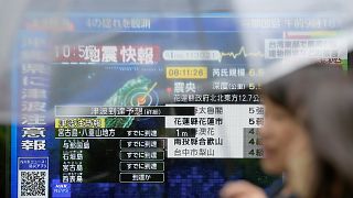 Varias personas caminan por una acera junto a un televisor que muestra las últimas noticias sobre los daños causados por el terremoto en Taiwán, el 3 de abril de 2024.