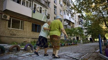 Einheimische Frauen gehen in der Nähe eines Wohnhauses spazieren, das durch einen russischen Angriff in Pawlohrad beschädigt wurde, 6. September 2024