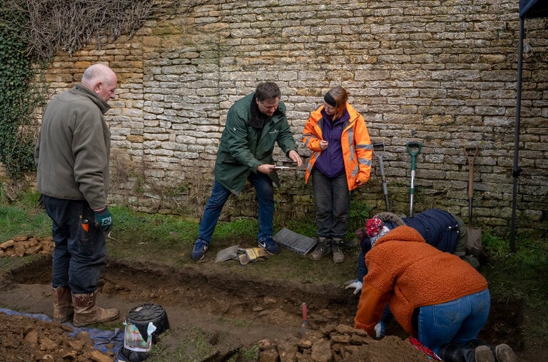 Chris Close, center left, in green jacket, consulting with Jennifer Browning, an archaeologist, during work on the dig site in Collyweston, England, early this year.