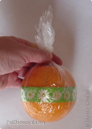 Теперь упакуем апельсин в пищевую плёнку. Закрутим концы плёнки узелком (фото 22)