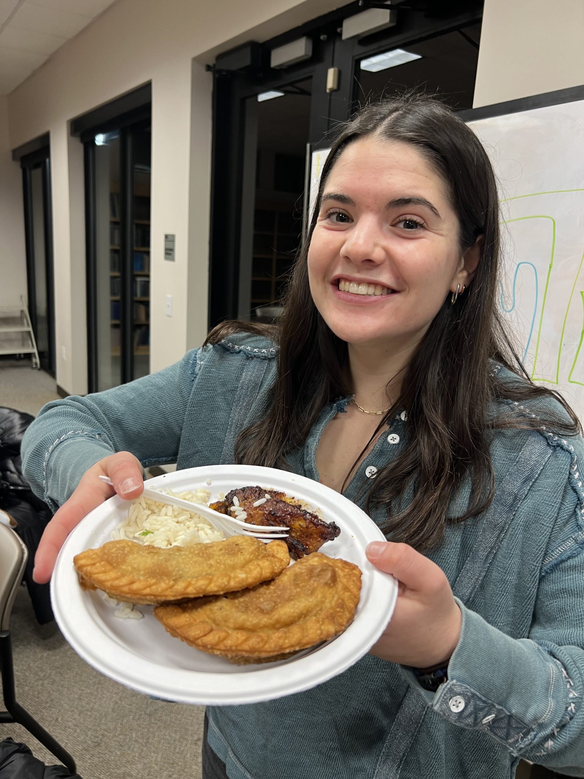 student holds plate of empanadas and platanos