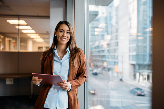 Portrait of happy businesswoman with touchpad in office looking at camera.