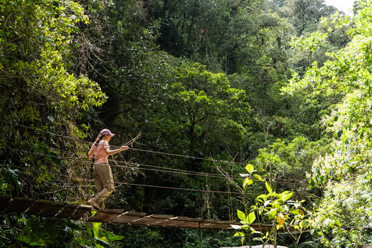 mujer practicando senderismo y pasando puente colgante