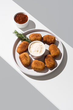 Plato de croquetas fritas con salsa de tomate y mayonesa aperitivo sobre fondo gris	