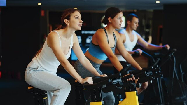 Sportive young woman doing spin bike exercises in well-equipped gym during training session