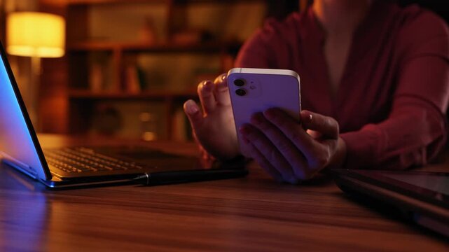 A woman works on a computer and a smartphone, a close-up of a laptop keyboard. Text message for customers. Businesswoman, digital technologies. Cinematic light, evening, stylish office.