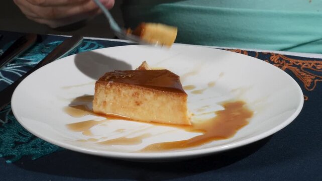 Quesillo venezuelan flan typical dessert with rich caramel, woman hands test with spoon