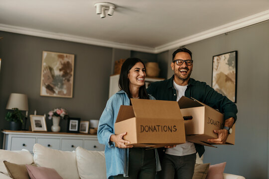 Husband and wife man and woman couple stand at home holding donation boxes in their apartment living room