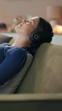 Girl, calm and relax with music on sofa for enjoyment, chilled vibe and unwind on weekend break for stress relief. Woman, eyes closed and headphones in home for radio, happy and comfortable on couch.