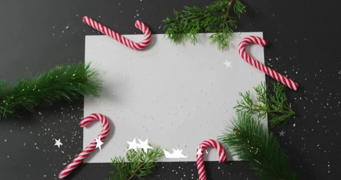 Animation of white paper with copy space and christmas decorations on black background