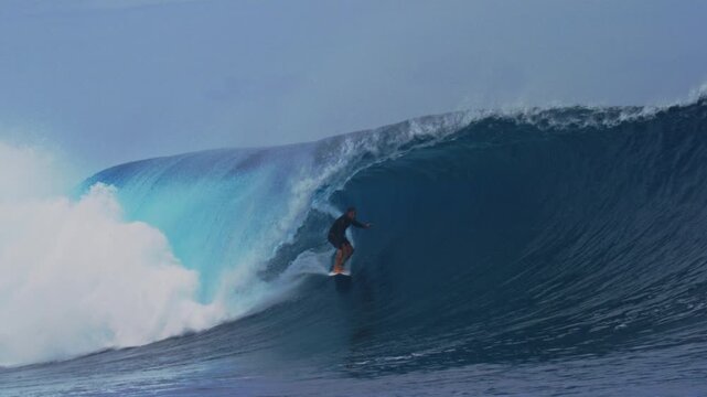 Surfer stands upright and crouches down deep in barrel, slow motion Cloudbreak Fiji