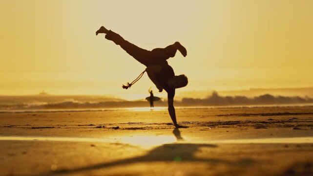 A man is dancing kapoeira - on the beach in the sun