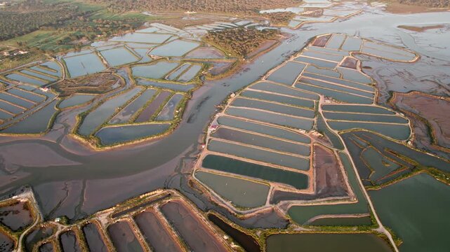 Stunning aerial shot capturing the geometric beauty of salt extraction basins with water reflecting the sky.