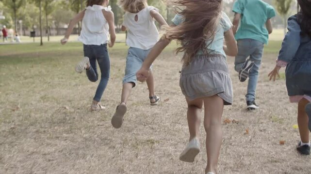 Rear View Of Children Running And Competing In Speed In The Park