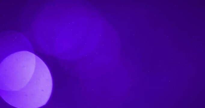 Animation of glowing light spots moving over purple background