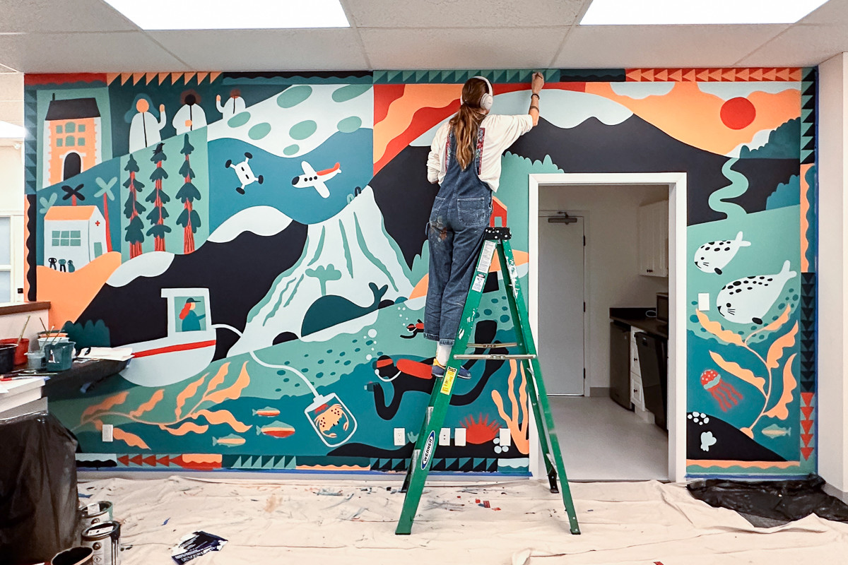 Woman painting mural in the Tula Foundation headquarters.