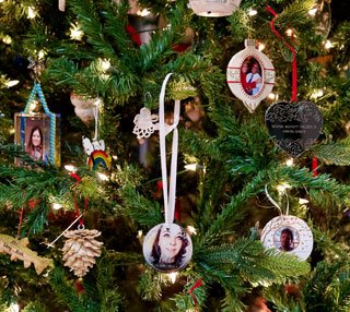 close-up of evergreen tree with variety of ornaments showing faces