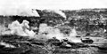 At numerous points, however, severe fighting continued. Tanks are shown reducing an enemy position. Center tank was knocked out but was protected from capture by others. Shell burst mark location of Japanese.