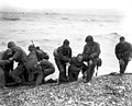 Members of an American landing party lend helping hands to other members of their organization whose landing craft was sunk be enemy action of the coast of France. These survivors reached Omaha Beach, by using a life raft.