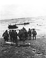 GIs who have landed on the northern coast of France during the early stages of D-Day man a life line to help other Americans approaching the beach in a swamped landing craft. 12 June 1944