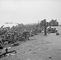 Troops crouch down on Sword Beach as they wait the signal to advance - 6 June 1944