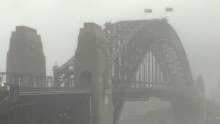 The Sydney Harbour Bridge stands amid a grey sky as torrential rain batters the city.