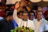 Sri Lankan President Maithripala Sirisena stands at a podium and waves. 