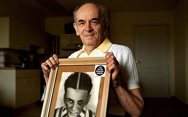 In this 2001 photo, Alter Wiener, born in 1926, holds up a photo of himself taken in July 1945, two months after he was liberated from a Nazi death camp, in his apartment in Aloha, Oregon. (Benjamin Brink/The Oregonian via AP)