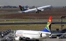 FILE: A South African Airways flight takes off as another one is parked in a bay on the tarmac at OR Tambo International airport in Johannesburg. Picture: AFP
