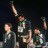 US athletes Tommie Smith, center, and John Carlos stare downward during the playing of national anthem after Smith received the gold and Carlos the bronze for the 200-metre sprint at the 1968 Olympic Games in Mexico City. Australian silver medalist Peter Norman is at left.