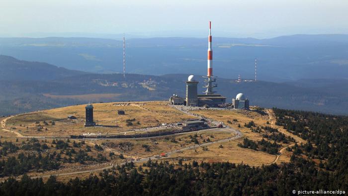 Auf dem Gipfel eines Berges stehen zwei kleine Gebäude mit Kuppeln und ein großer Mast. © picture alliance/dpa 