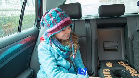 Emma sitzt auf der Rückbank im Auto und legt mit Buchstabenkeksen verschiedene Wörter (DW)