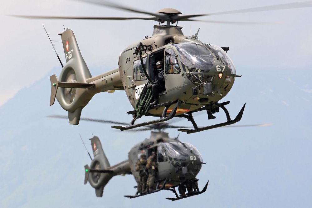 Two Airbus H135M military helicopters in the armed scout configuration fly in formation.  