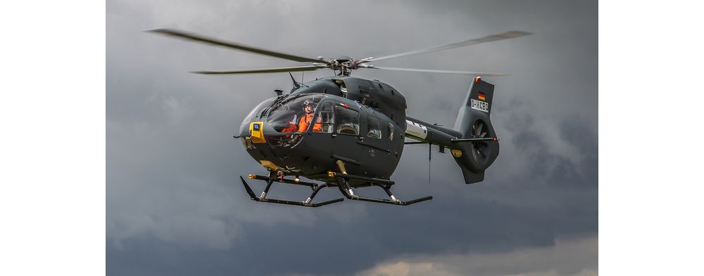 An in-flight Airbus H145M helicopter with a clear view of the pilot inside. 