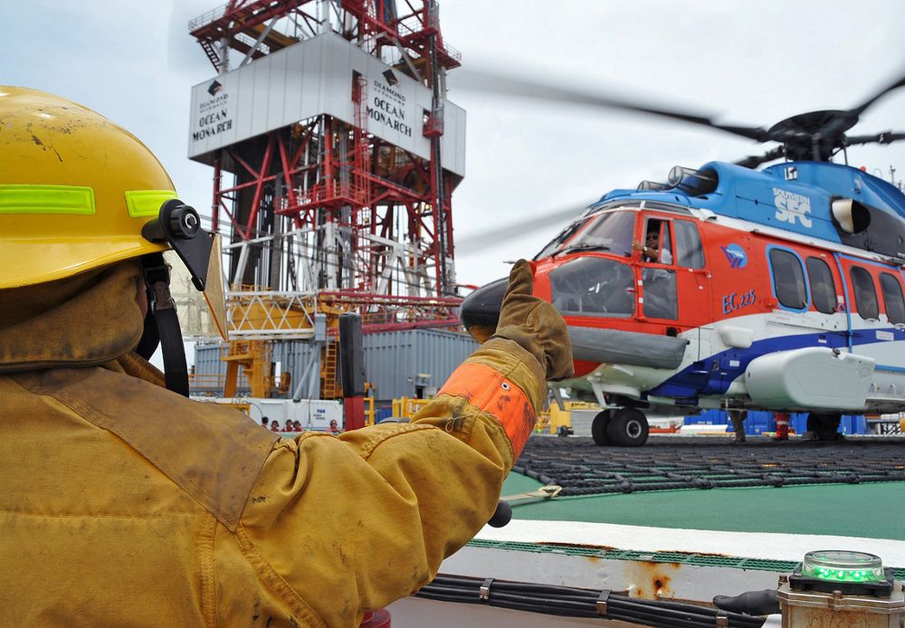 An oil and gas worker signals the pilot inside an Airbus H225 helicopter. 