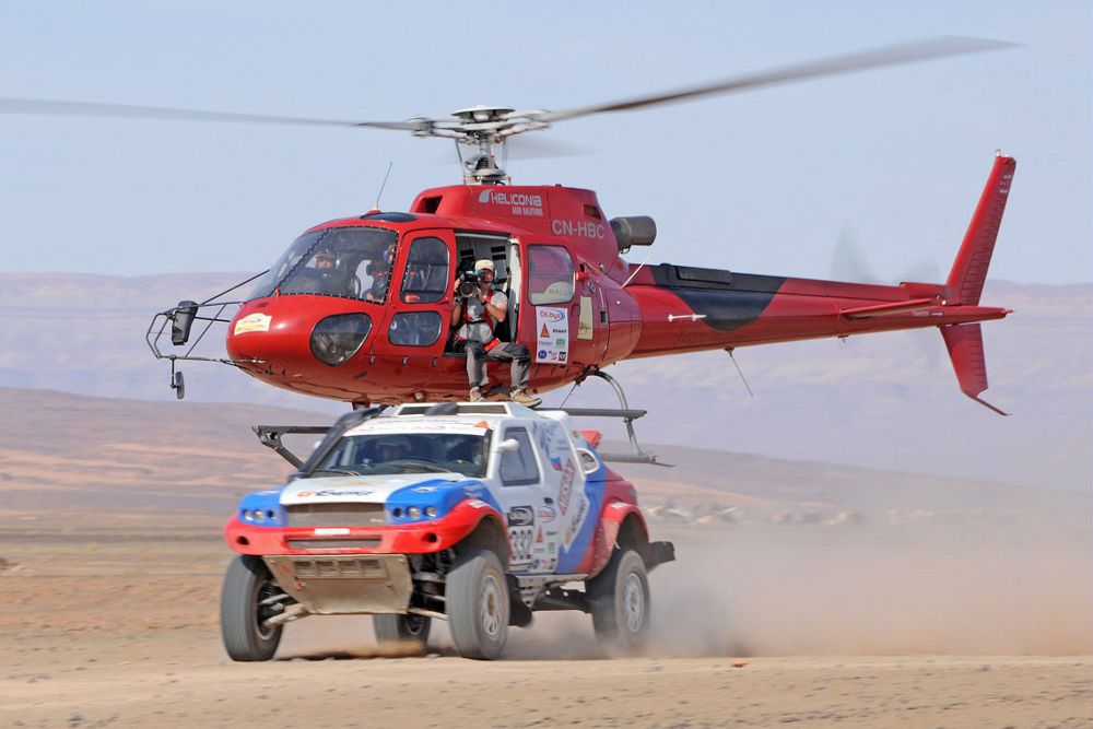 An Airbus H125 helicopter flies low to film an off-road race.  