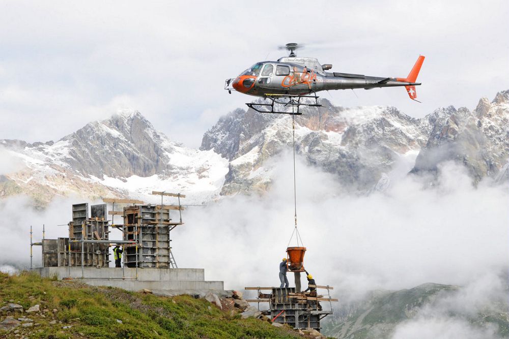 An Airbus H125 helicopter performs aerial work duties in a mountainous area.  