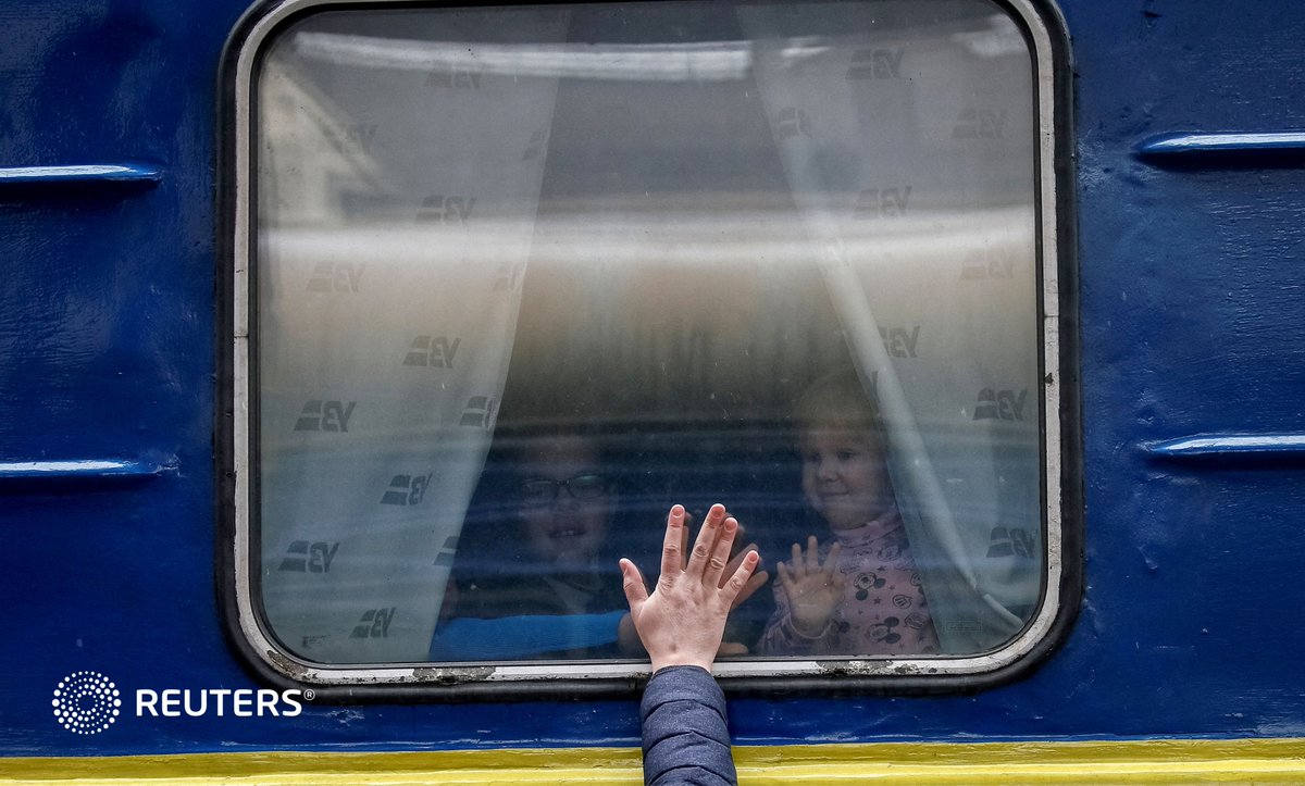 Children look out from an evacuation train from Kyiv to Lviv, saying goodbye to their father at Kyiv...