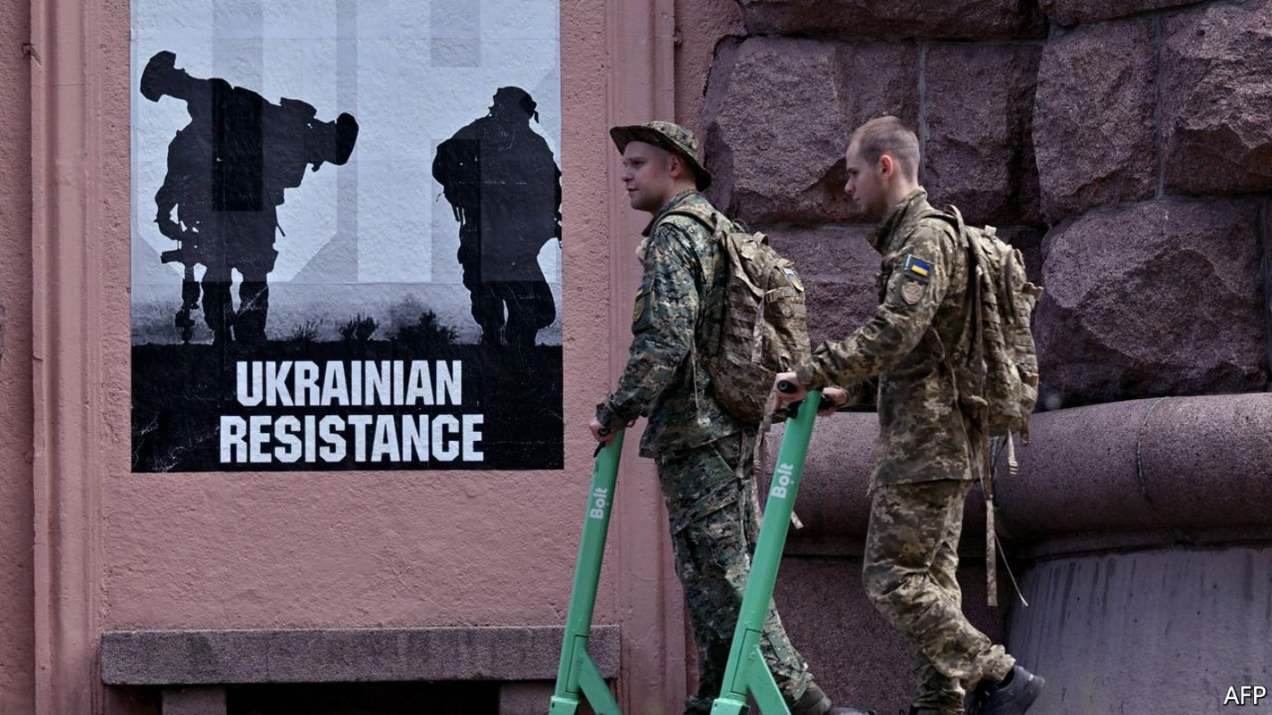 Ukrainian servicemen ride electric scooters past a poster reading "Ukrainian resistance" in the center of Kyiv on June 1, 2022 amid the Russian invasion of Ukraine. (Photo by Sergei SUPINSKY / AFP)