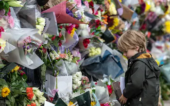 A young boy lays flowers outside Buckingham Palace
