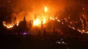 The McDougall Creek wildfire burns on the mountainside above a lakefront home, in West Kelowna, B.C., on Friday, August 18, 2023. THE CANADIAN PRESS/Darryl Dyck 