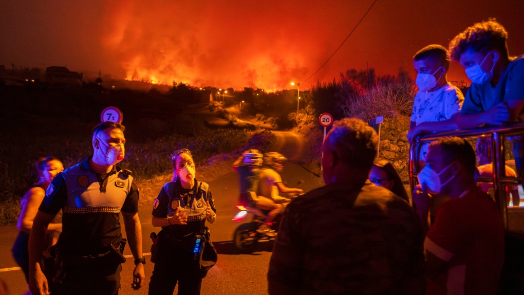 Local residents try to reach their houses in Benijos village as police block the area as fire advances in La Orotava in Tenerife, Canary Islands, Spain on Saturday, Aug. 19, 2023. (AP Photo/Arturo Rodriguez)