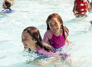 Josh Cobb/News Tribune photo: The Memorial Park Family Aquatic Center was full of people taking a break from the heat wave on Wednesday afternoon, June 28, 2023. Ten year old Alana Hess (left) carries her sister seven year old Adalyn Hess through the water.