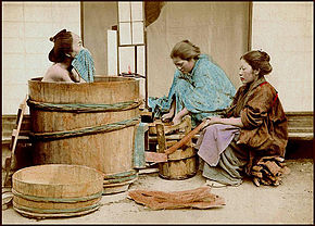 Samurái en su ofuro, con una tina y un barreño también de madera y asistido por dos sirvientas.
