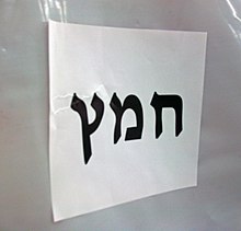 "Chametz" in large black Hebrew letters on a letter-size piece of paper, affixed horizontally to white plastic background.