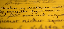 Photo of black handwritten text on a seemingly yellow paper with the top and bottom blurry and vertical middle clear